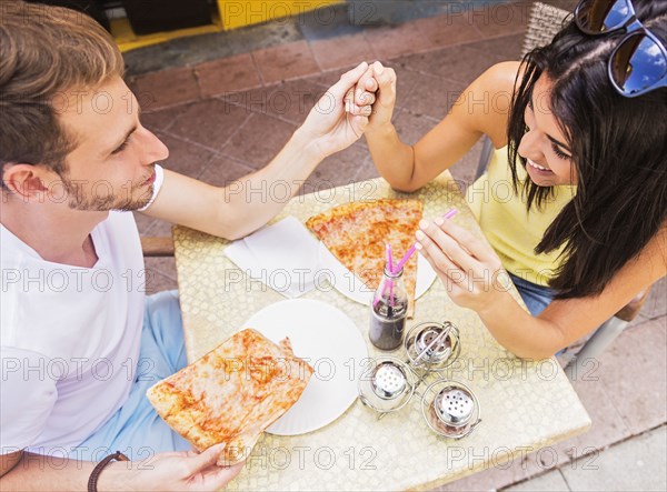 Hispanic couple eating pizza at cafe