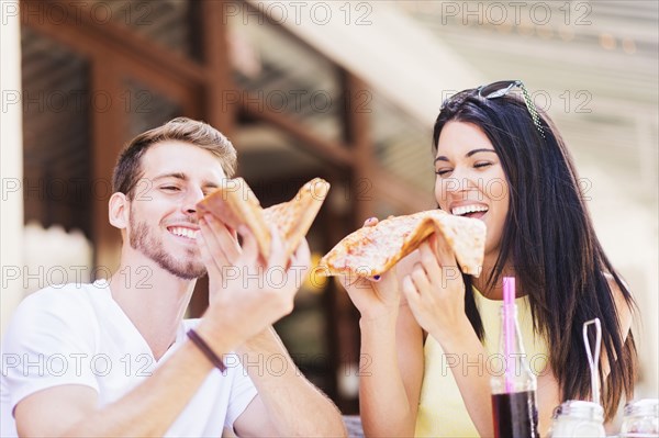 Hispanic couple eating pizza at cafe