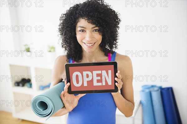 Mixed race woman holding open sign in yoga studio