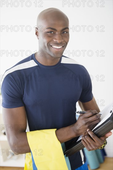 Black trainer writing notes in yoga studio