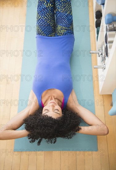 Mixed race woman doing sit-ups in gym