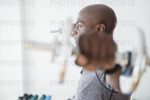 Black man lifting weights in gym