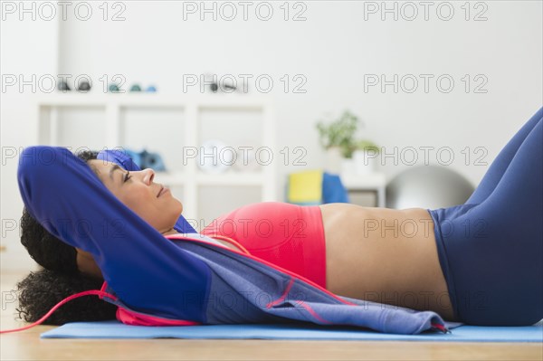 Mixed race woman doing sit-ups in gym