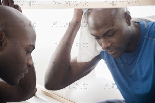 Black man resting near mirror after workout