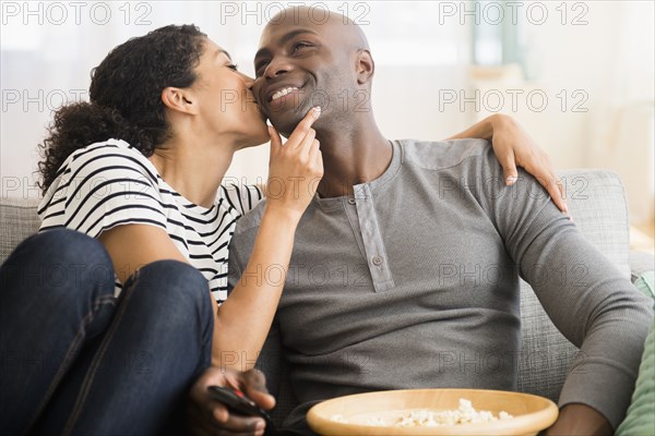 Smiling couple watching television on sofa