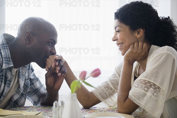Man kissing hand of girlfriend at restaurant table