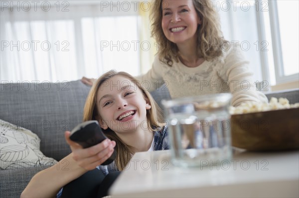 Caucasian mother and daughter watching television on sofa