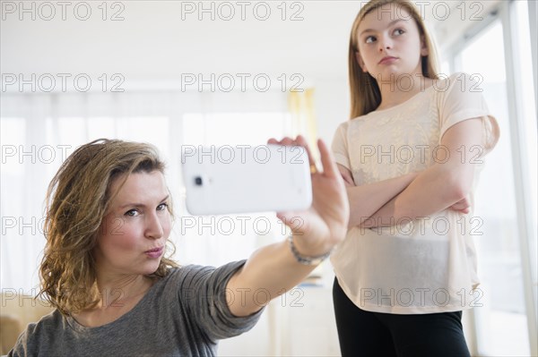 Caucasian girl embarrassed of mother taking selfies with cell phone