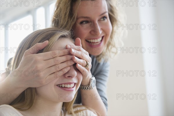 Caucasian mother covering eyes of daughter