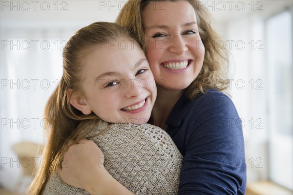 Caucasian mother and daughter hugging in living room