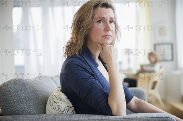 Concerned Caucasian woman sitting on sofa