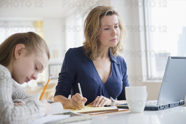 Caucasian mother and daughter working at desk