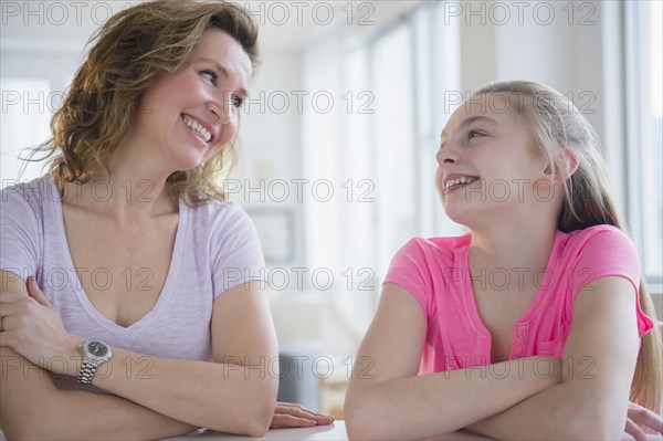 Caucasian mother and daughter laughing at table