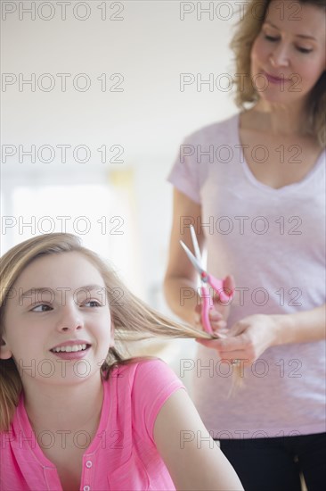 Caucasian mother cutting hair of daughter