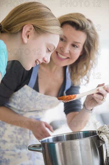 Caucasian mother and daughter cooking sauce in pot