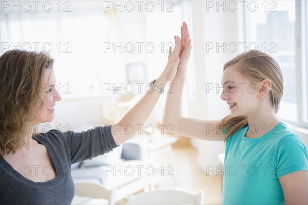 Caucasian mother and daughter high fiving in living room