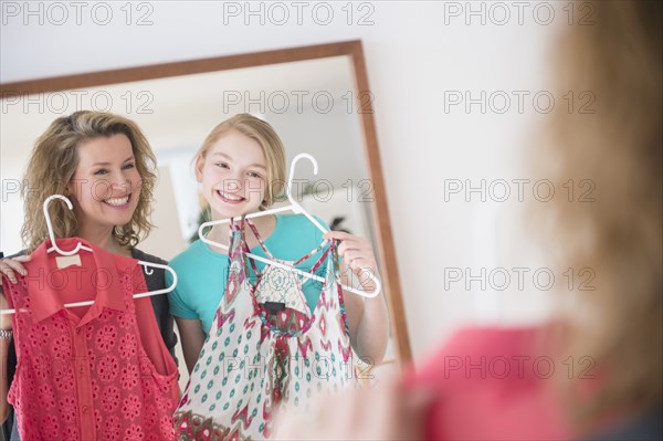 Caucasian mother and daughter examining shirts in mirror