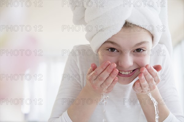 Caucasian girl washing face in bathroom