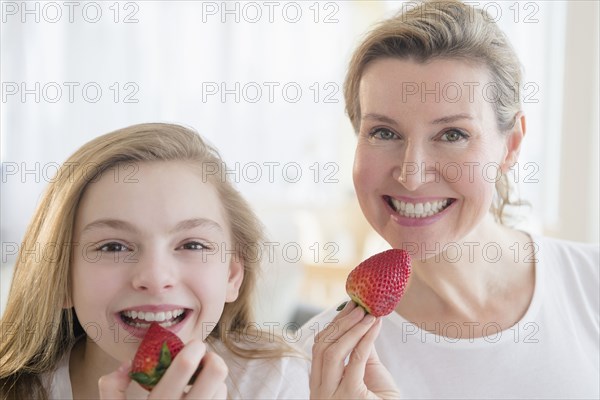 Caucasian mother and daughter eating strawberries