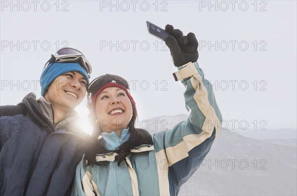 Couple in winter clothing taking selfie near mountain