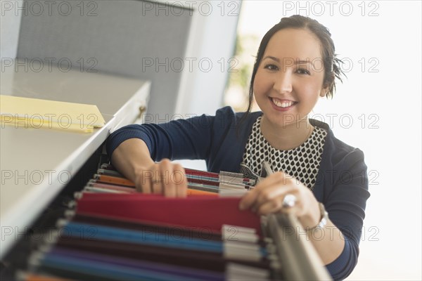 Mixed race businesswoman choosing files in office