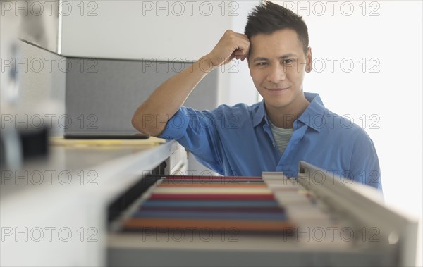 Chinese businessman smiling near filing cabinet