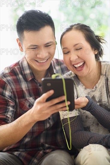 Laughing couple watching digital tablet on sofa