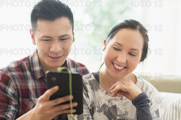 Laughing couple watching digital tablet on sofa