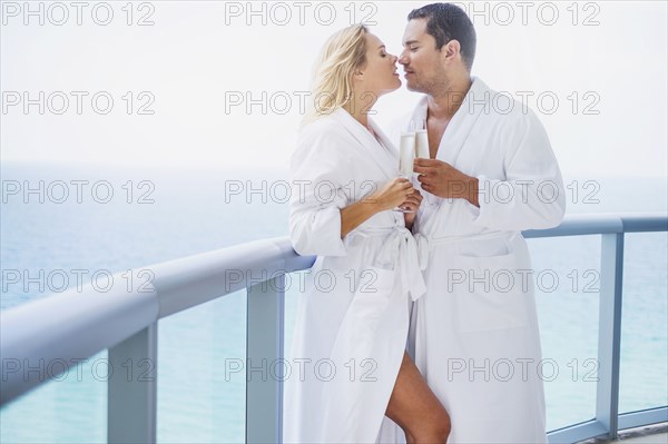 Couple kissing with champagne on balcony