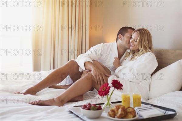 Couple enjoying breakfast in bed in hotel room