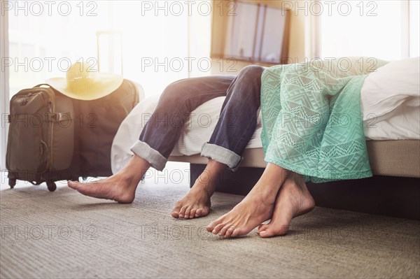 Legs of couple laying on bed in hotel room