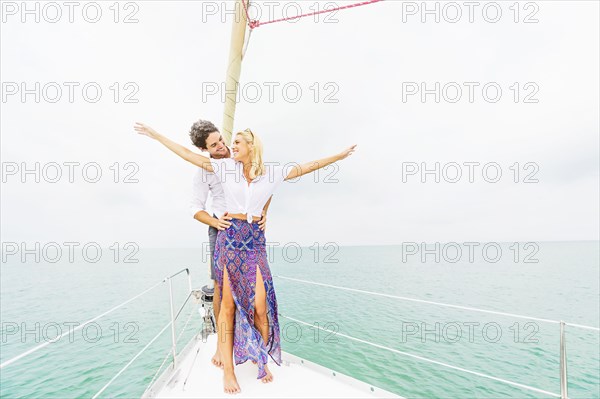 Couple standing on deck of sailboat