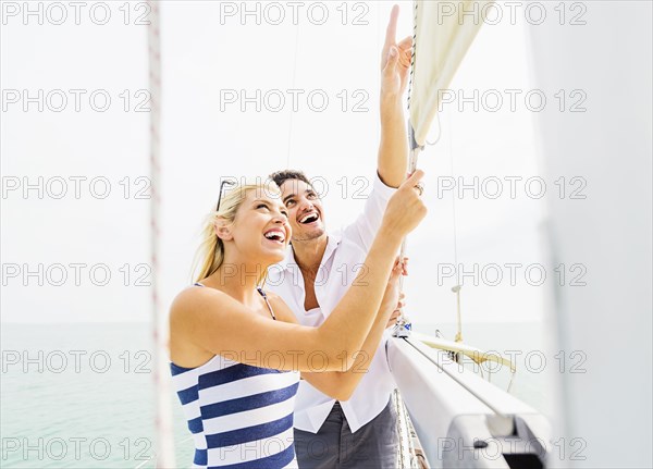 Couple adjusting rigging on sailboat