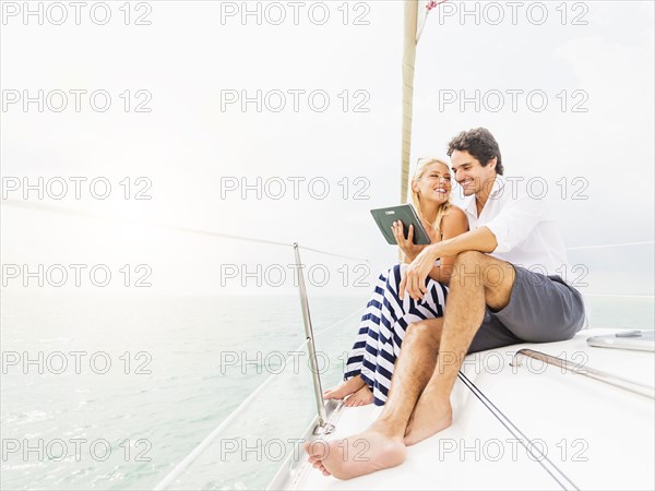 Couple using digital tablet boat deck