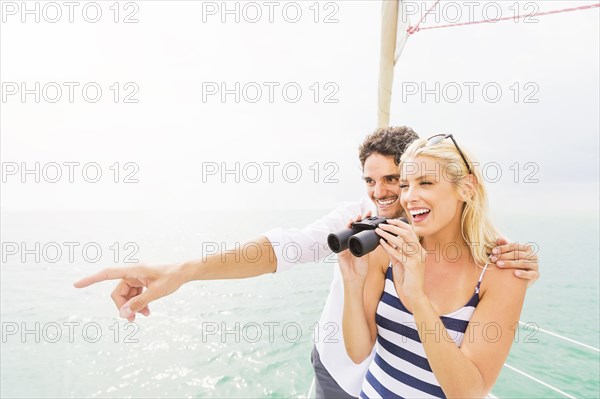 Couple looking out from boat deck with binoculars