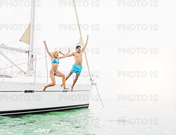 Couple jumping from sailboat