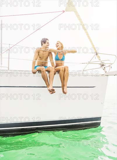 Couple sitting on deck of sailboat