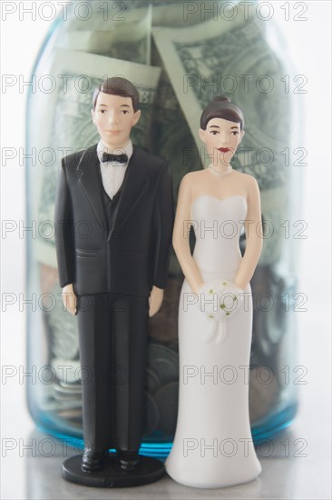 Close up of bride and groom dolls near savings jar