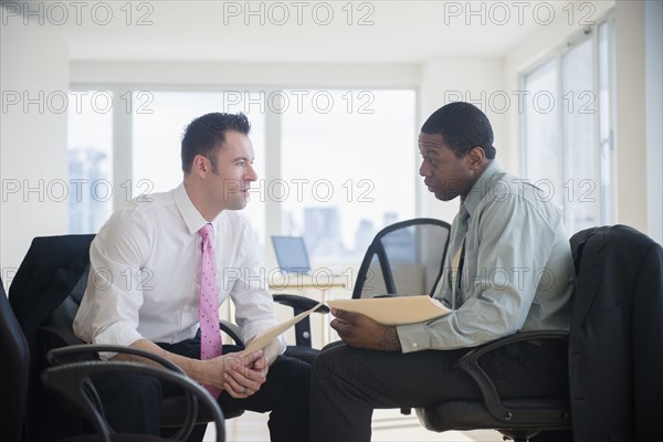 Businessmen holding folders in office