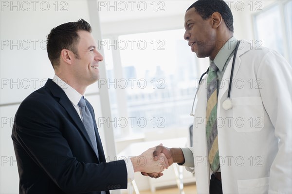 Businessman and doctor shaking hands in office