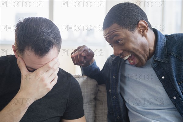 Close up of man teasing friend on sofa