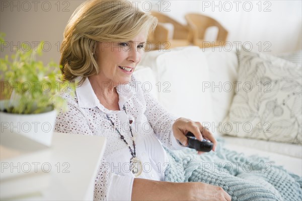 Caucasian woman watching television on sofa