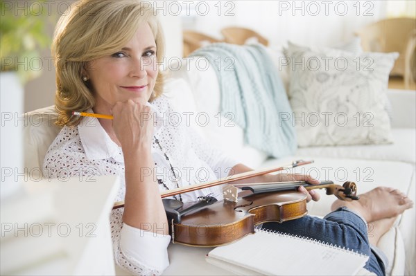 Caucasian woman holding violin on sofa