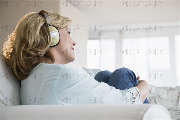 Caucasian woman listening to headphones on sofa