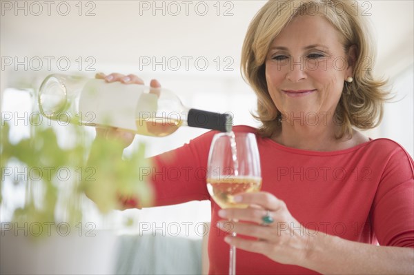 Caucasian woman pouring glass of white wine