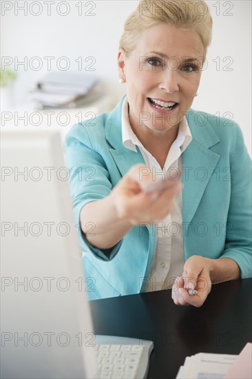 Caucasian businesswoman offering business card in office