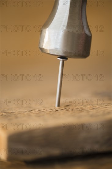 Close up of hammer and nail in wooden board