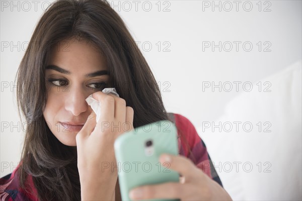 Sad woman crying and using cell phone