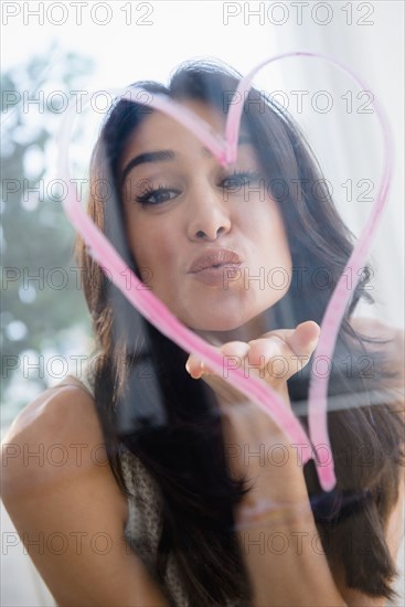 Close up of woman blowing a kiss through heart