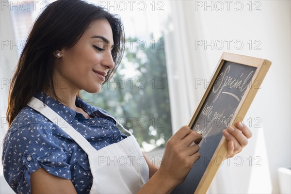 Woman writing specials on cafe chalkboard